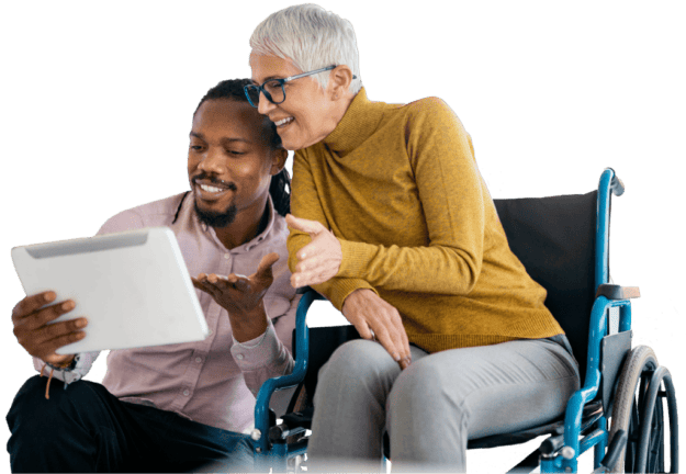 An image of a lady in a wheelchair and a man reading a tablet