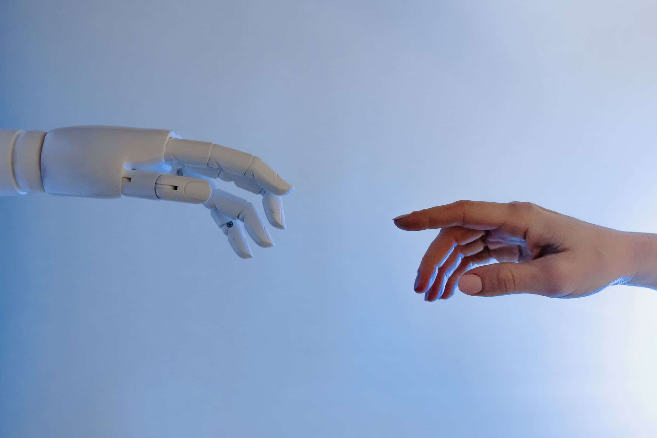 Robot og menneskehånd peger på hinanden